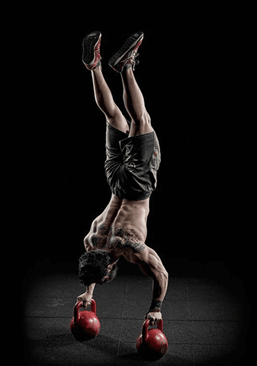Athlete doing handstand on kettlebells